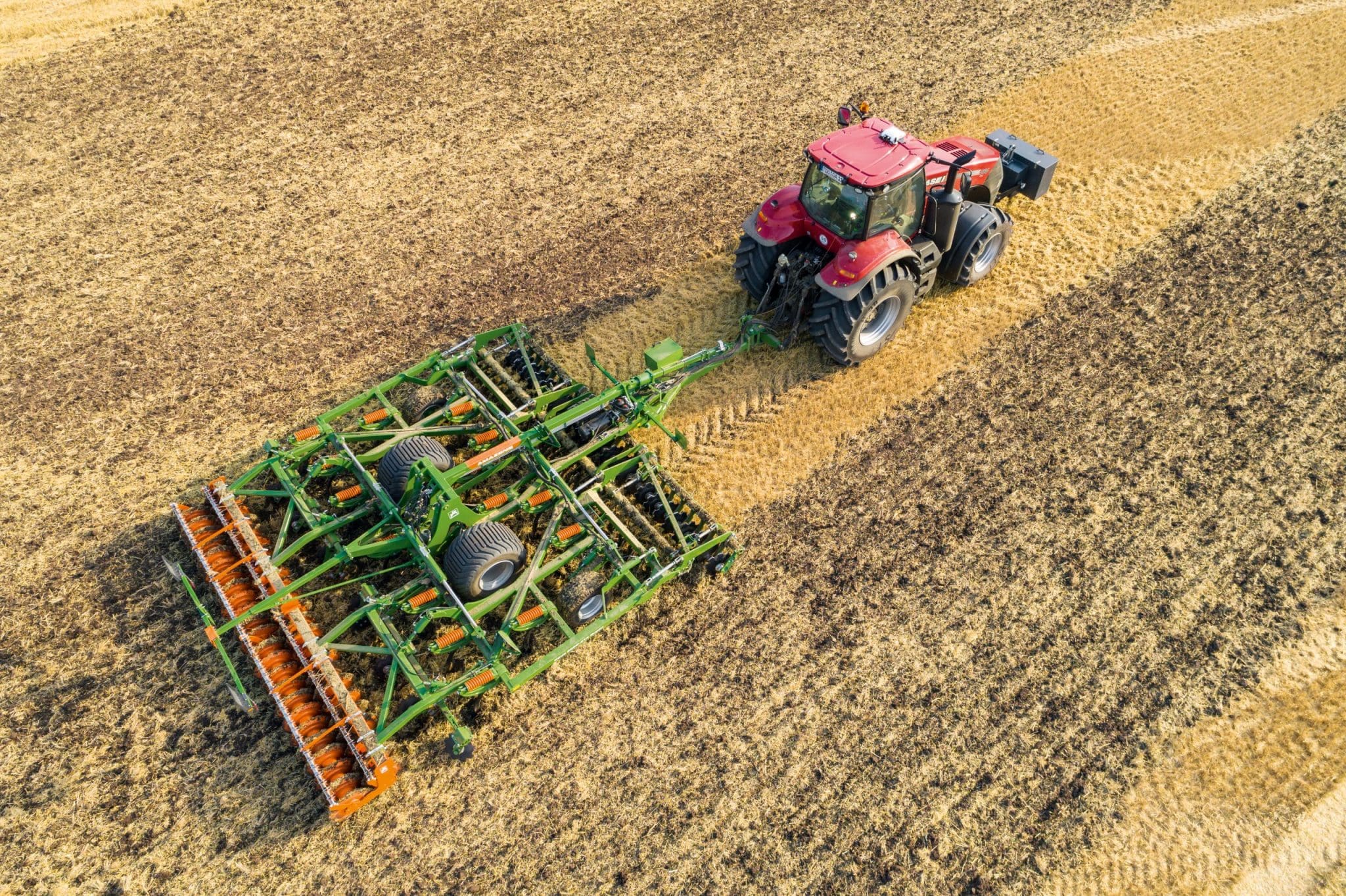Aerial shot of tractor and amazone ceus combination cultivator in field